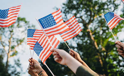 A crowd of people, waving flags in celebration of Veteran's Day